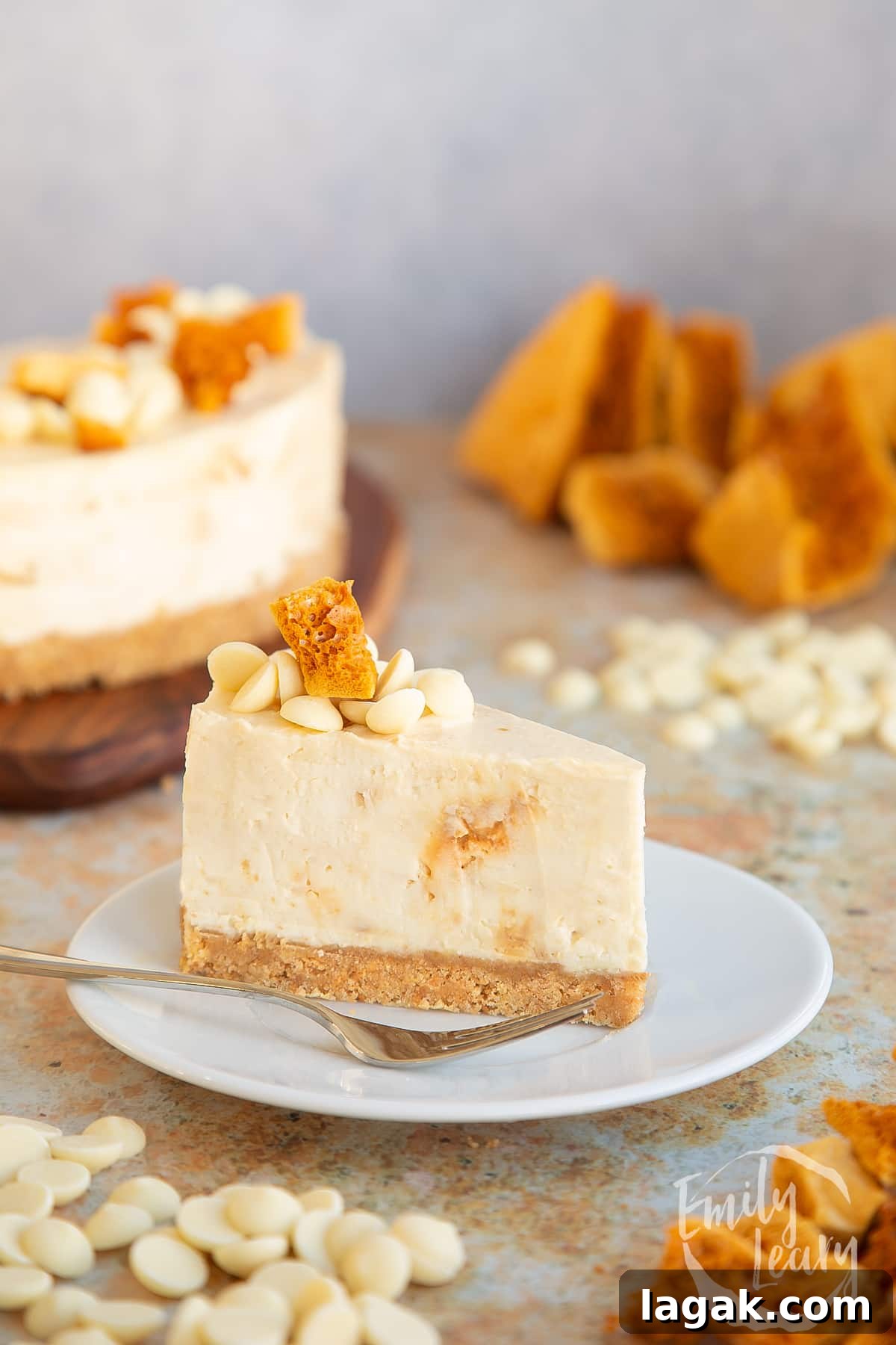 slice of white chocolate and honeycomb cheesecake placed on a white plate with a fork on the side